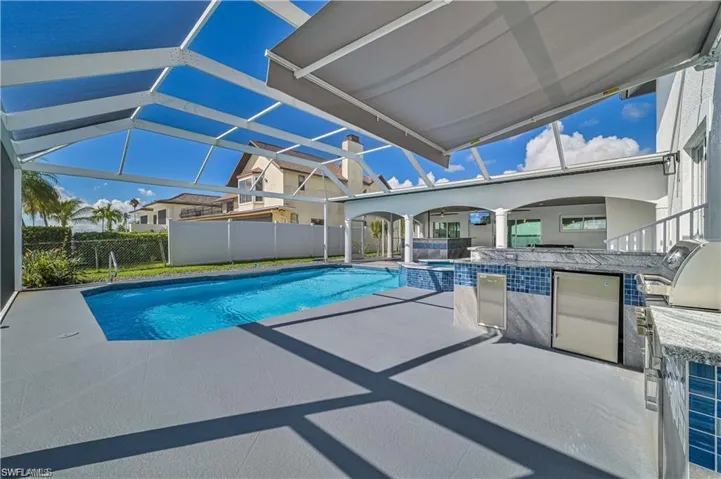 View of swimming pool with a patio, area for grilling, a pool with connected hot tub, and a lanai