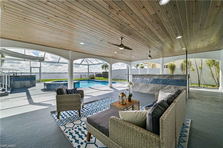 View of patio / terrace featuring an outdoor hangout area, a pool with connected hot tub, glass enclosure, and a ceiling fan