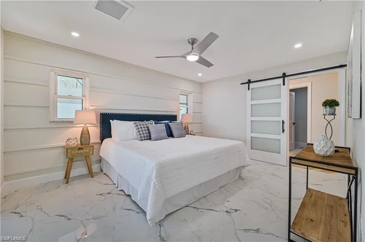 Bedroom featuring a barn door, marble finish floors, recessed lighting, and ceiling fan