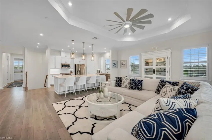 Living area featuring plenty of natural light, light wood-style flooring, crown molding, and a tray ceiling