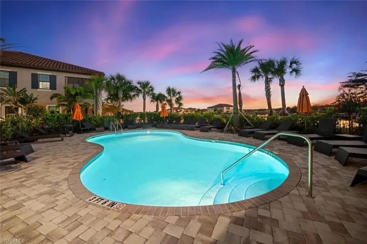 Pool at dusk featuring a patio area and a community pool