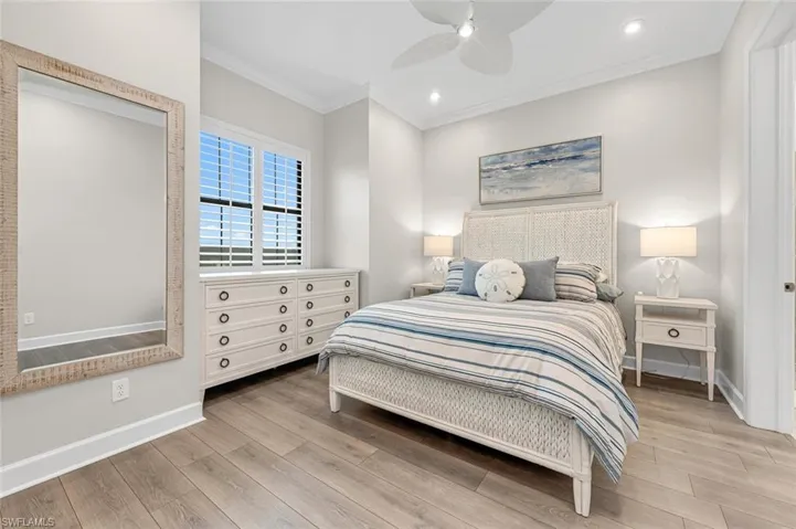 Bedroom with ceiling fan, baseboards, wood finished floors, and ornamental molding