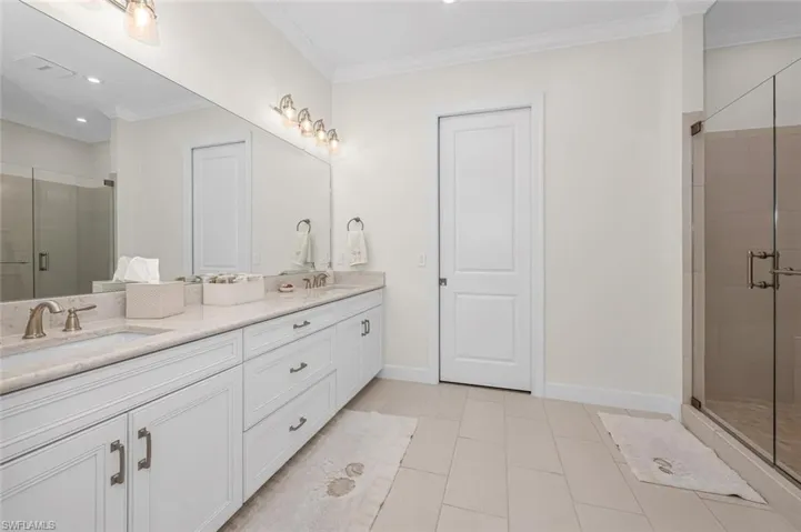 Full bath with ornamental molding, baseboards, a stall shower, and a sink