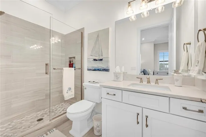 Full bath with toilet, ornamental molding, connected bathroom, a shower stall, and vanity