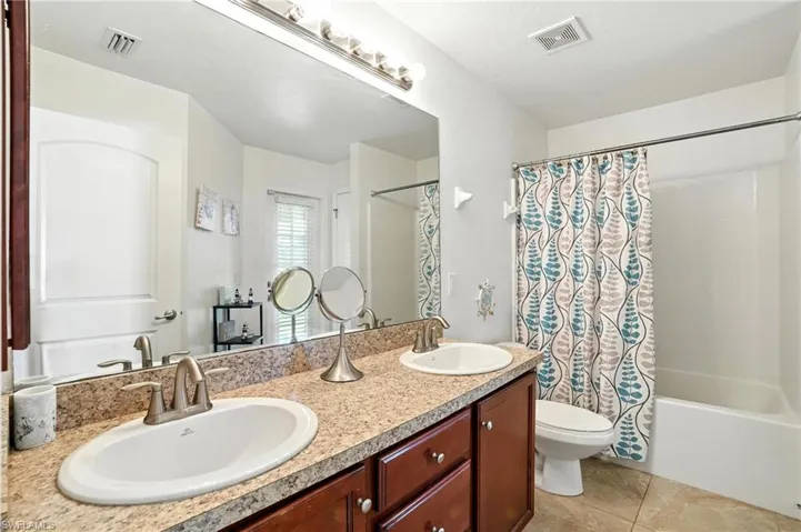 Full bath featuring double vanity, shower / bath combination with curtain, and tile patterned floors