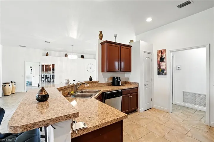 Kitchen featuring a peninsula, stainless steel dishwasher, a breakfast bar area, and light tile patterned flooring