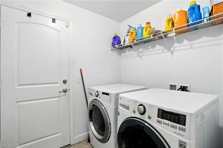 Laundry area with separate washer and dryer and light tile patterned floors