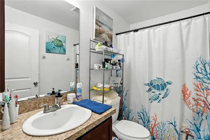 Bathroom with vanity, curtained shower, and a textured wall