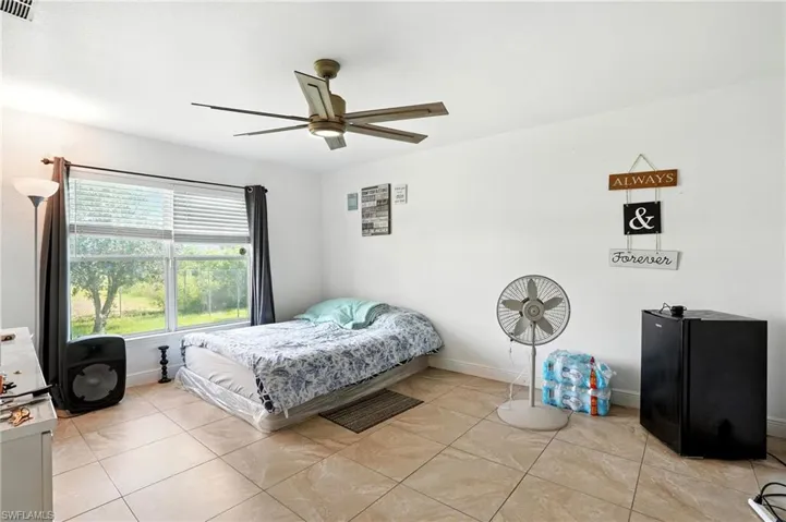 Bedroom with light tile patterned floors and a ceiling fan