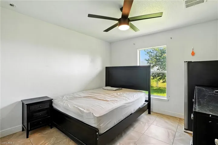 Bedroom with freestanding refrigerator and ceiling fan