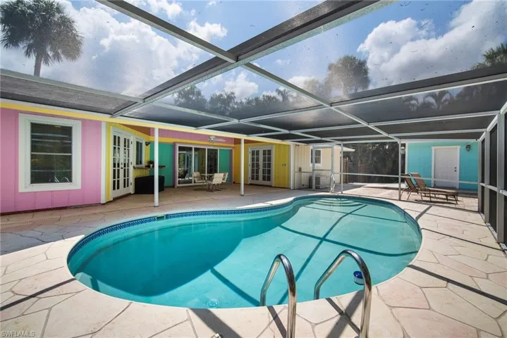 View of pool with glass enclosure, a patio area, and french doors