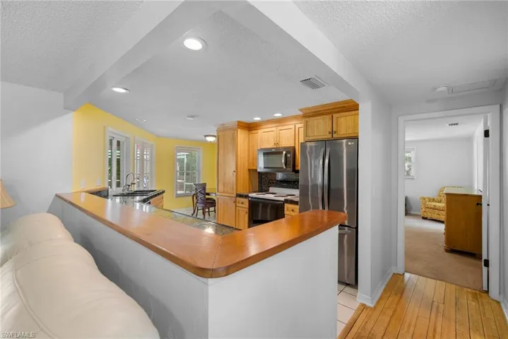 Kitchen featuring light hardwood / wood-style flooring, kitchen peninsula, a textured ceiling, sink, and appliances with stainless steel finishes