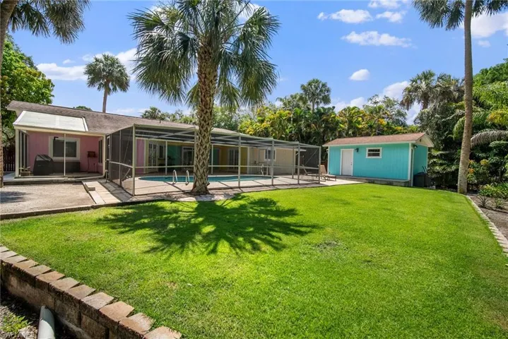 View of yard featuring an outdoor structure, glass enclosure, and a patio area
