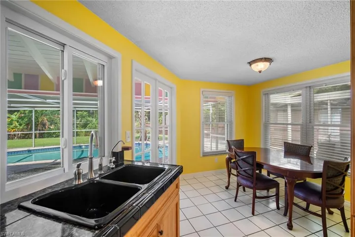 Kitchen with sink, tile countertops, light tile flooring, and a textured ceiling