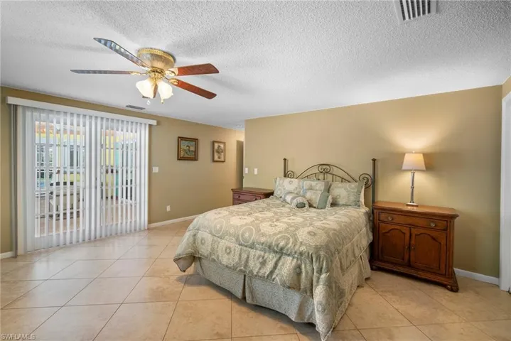 Tiled bedroom with ceiling fan and a textured ceiling