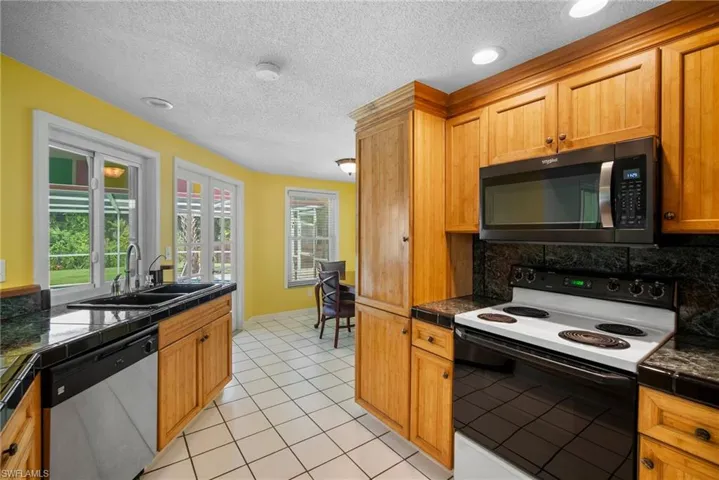 Kitchen featuring stainless steel appliances, light tile floors, sink, and a textured ceiling