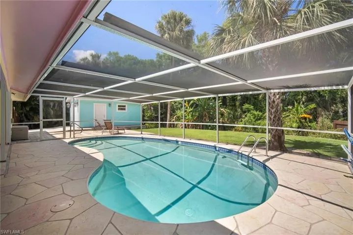 View of swimming pool featuring glass enclosure, a patio area, and a yard