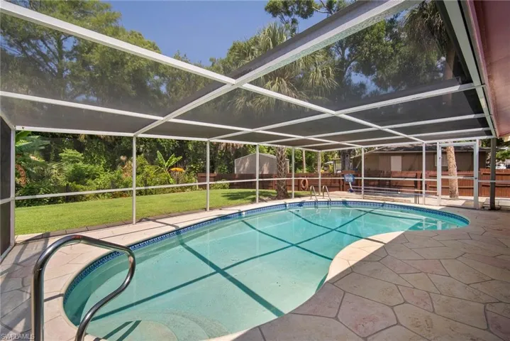 View of pool with a yard, glass enclosure, and a patio