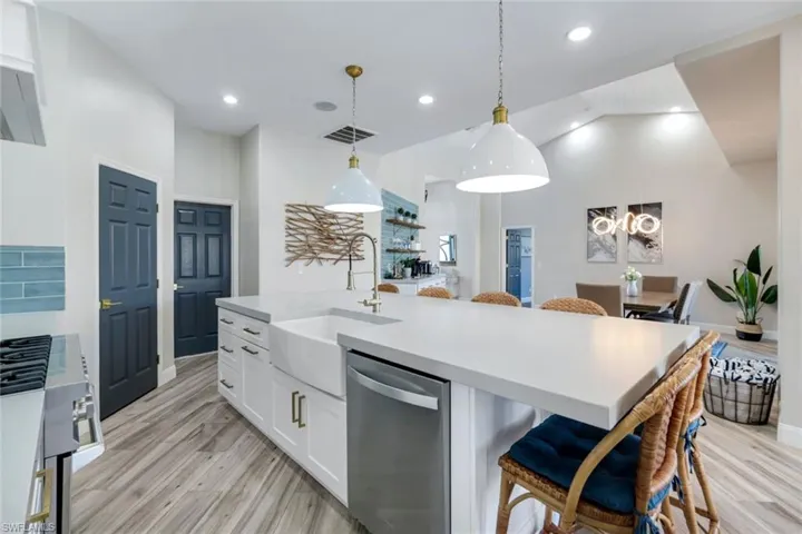 Kitchen featuring appliances with stainless steel finishes, a sink, white cabinets, light wood finished floors, and recessed lighting