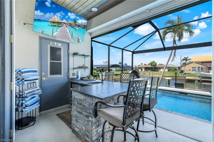 View of patio / terrace with a lanai, an outdoor pool, and a water view