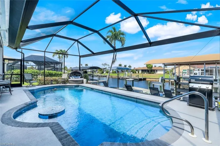 Swimming pool with boat lift, a water view, and a boat dock