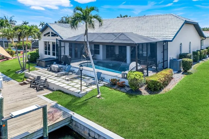 Rear view of house featuring a covered hot tub, a tile roof, a patio area, and a yard