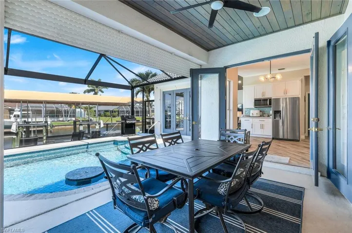 View of patio with french doors, a ceiling fan, an outdoor pool, glass enclosure, and a grill