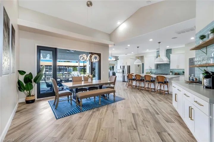 Dining space featuring light wood finished floors, a chandelier, lofted ceiling, and baseboards