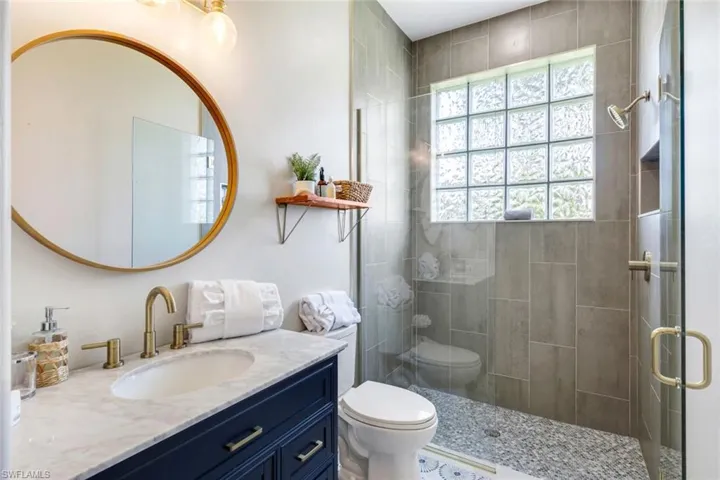 Full bathroom with toilet, vanity, and tiled shower