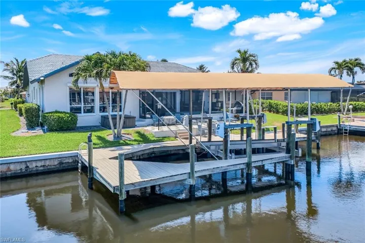 Dock area featuring a water view, boat lift, and a patio area