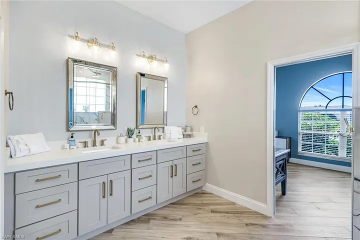 Bathroom featuring double vanity, wood finished floors, and baseboards