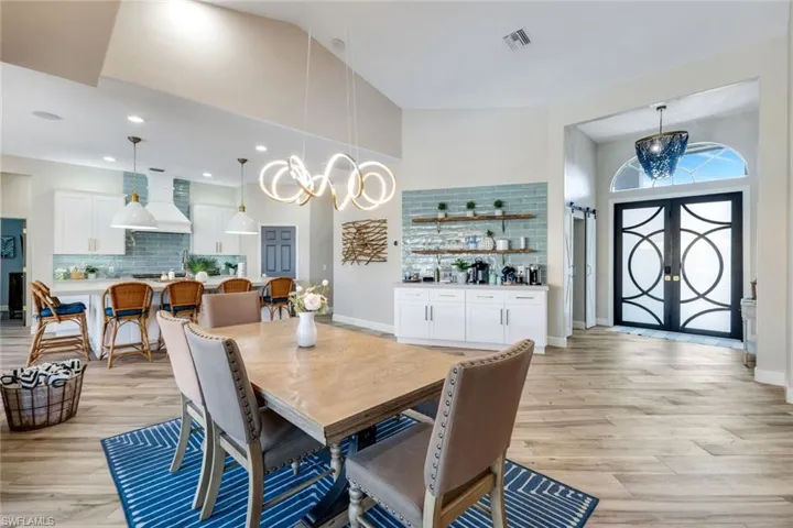 Dining space with light wood-style floors, a chandelier, and a high ceiling