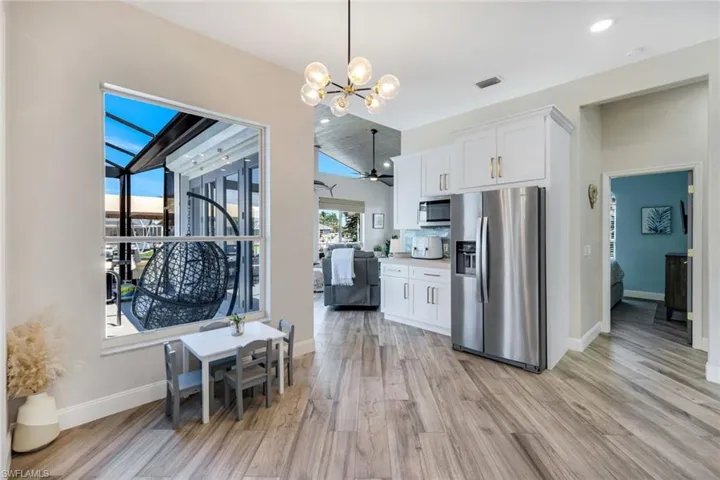 Kitchen featuring stainless steel appliances, light wood-style floors, a chandelier, white cabinets, and baseboards