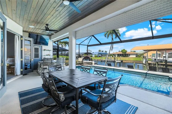 View of patio / terrace featuring a ceiling fan, a lanai, an outdoor pool, a dock, and boat lift