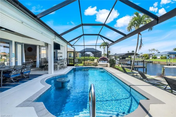 Outdoor pool featuring a patio, glass enclosure, and a water view