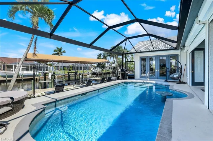 Outdoor pool featuring french doors, boat lift, a boat dock, a water view, and a patio