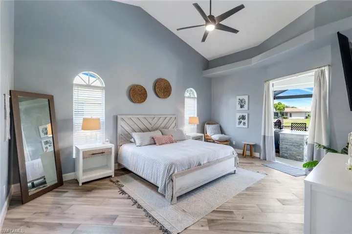 Bedroom featuring high vaulted ceiling, access to exterior, light wood-type flooring, baseboards, and ceiling fan