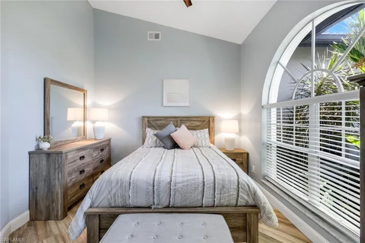 Bedroom with lofted ceiling, wood finished floors, and baseboards