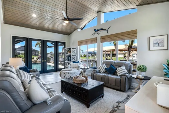 Living room with french doors, wood ceiling, a towering ceiling, light wood finished floors, and ceiling fan