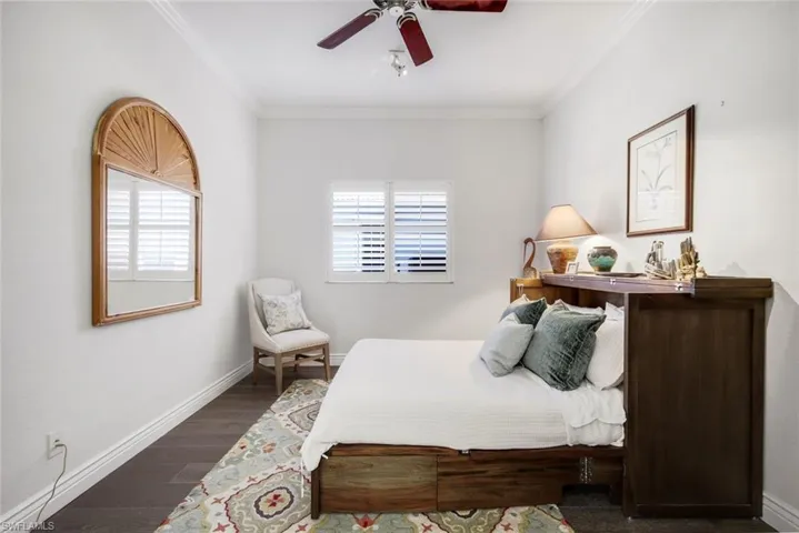 Bedroom with dark wood finished floors, a ceiling fan, and crown molding