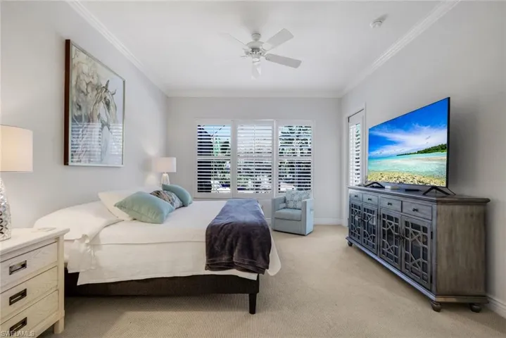 Carpeted bedroom featuring crown molding, multiple windows, and a ceiling fan