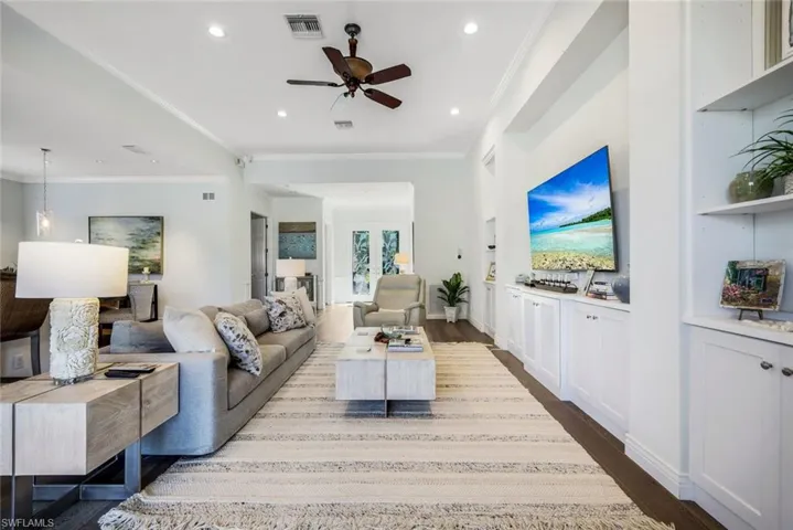 Living area with ornamental molding, ceiling fan, dark wood-type flooring, recessed lighting, and built in shelves