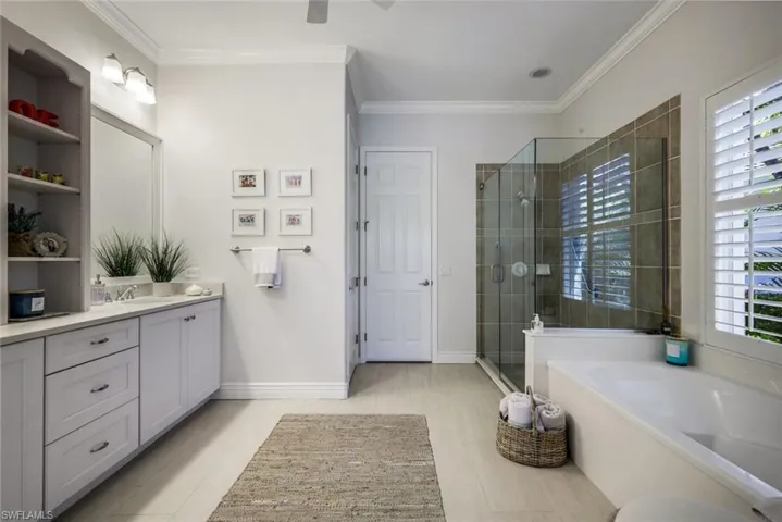 Full bathroom with a garden tub, vanity, a stall shower, crown molding, and ceiling fan