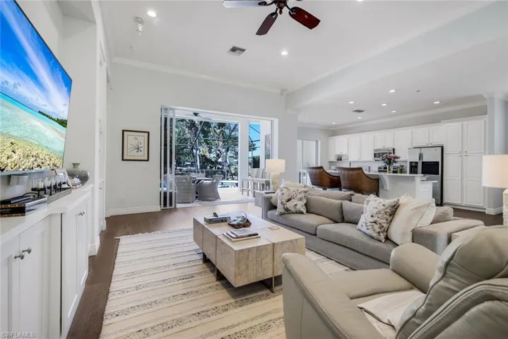 Living area with crown molding, a ceiling fan, wood finished floors, and recessed lighting