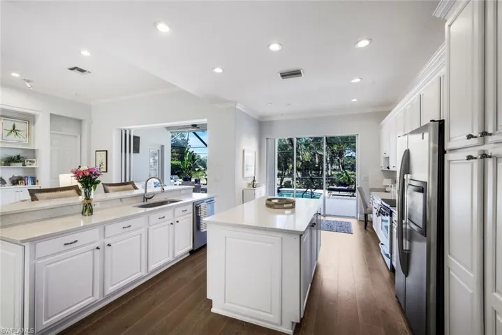 Kitchen with white cabinetry, stainless steel appliances, light stone countertops, recessed lighting, and ornamental molding