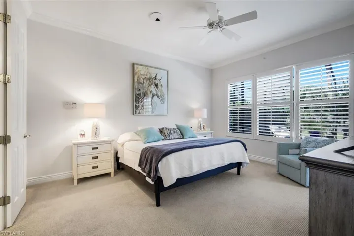 Bedroom with crown molding, light colored carpet, and a ceiling fan