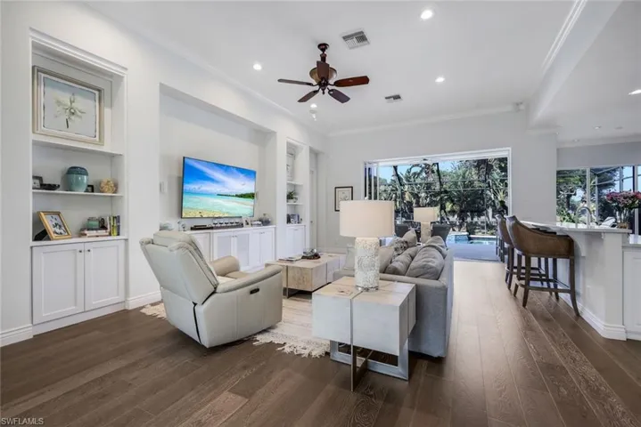 Living area featuring recessed lighting, dark wood-style floors, ceiling fan, crown molding, and built in features
