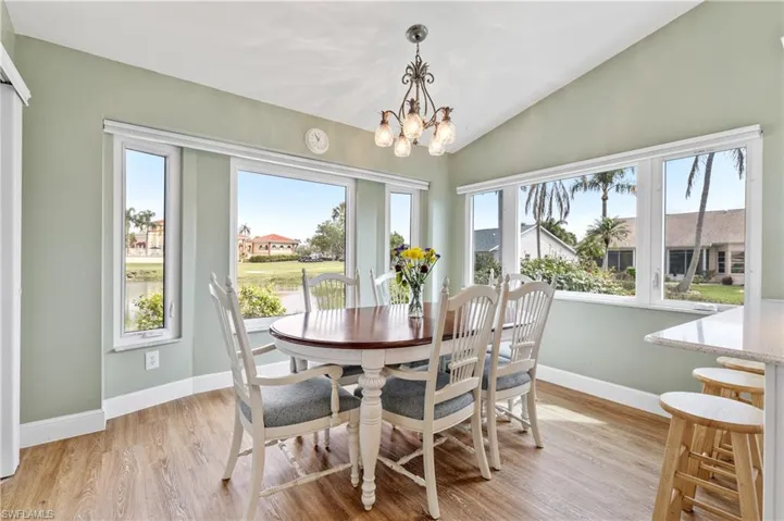 Dining room featuring vaulted ceiling, light wood-type flooring, and suspended lighting