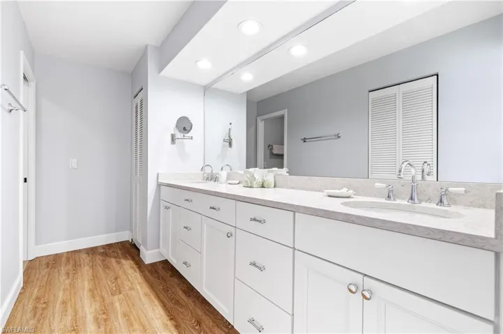 Full bath with a closet, double vanity, light wood-style flooring, and recessed lighting