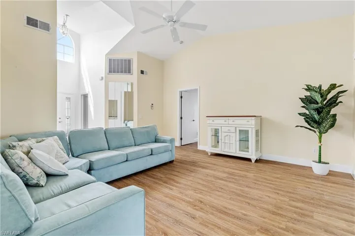 Living room featuring light wood-style flooring, lofted ceiling, and ceiling fan